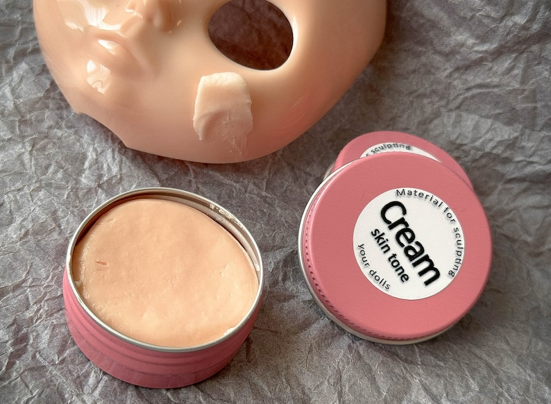 K&ouml;nnte beinhalten: Zwei rosa Beh&auml;lter mit Modelliercreme f&uuml;r Puppen. Ein Beh&auml;lter ist ge&ouml;ffnet und zeigt die rosa Creme im Inneren. Der andere Beh&auml;lter hat ein wei&szlig;es Etikett mit der Aufschrift "Material zum Modellieren Creme Hautton Ihre Puppen".
