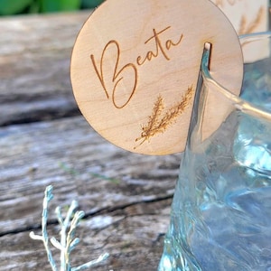 May include: A wooden drink marker with the name "Beata" engraved on it. The marker has a small design of a sprig of grass on it.