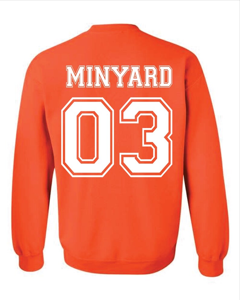 May include: Orange sweatshirt with the name "MINYARD" in white block letters across the upper back. Below the name is the number "03" in large white block letters. The sweatshirt has long sleeves and a crew neck.