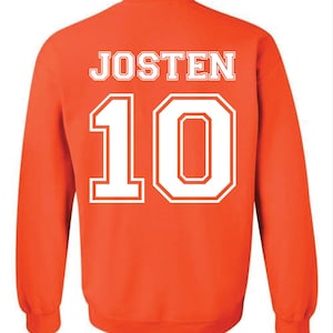 May include: An orange sweatshirt with the name "JOSTEN" in white block letters across the upper back and the number "10" in white, outlined block letters below. The sweatshirt has long sleeves and a crew neck.