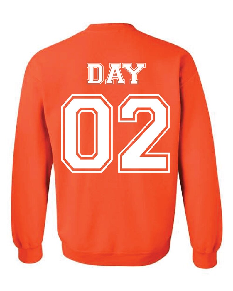 May include: Orange sweatshirt with white text that reads "DAY 02" on the back. The text is in a collegiate font. The sweatshirt has long sleeves and a crew neck.
