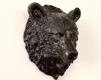 May include: A black bear head wall mount. The bear's fur is detailed and realistic. The bear's eyes are brown and the nose is black.