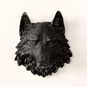 Könnte beinhalten: Schwarzer Wolfskopf Wanddekoration. Der Wolfskopf ist aus einem dunklen, strukturierten Material gefertigt und hat realistische Details, darunter Fell, Zähne und Augen.