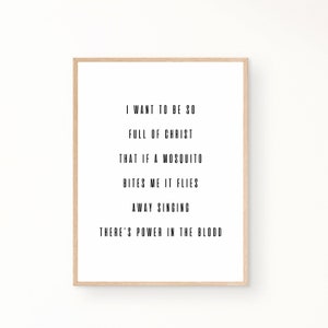 Op de afbeelding: Een zwart-witte printbare wandkunstprint met de tekst "Ik wil zo vol van Christus zijn dat als een mug me steekt, hij wegvliegt terwijl hij zingt, er is kracht in het bloed".