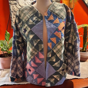 May include: A long-sleeve open-front jacket constructed from a patchwork of various fabric squares and triangles in shades of blue, green, and red, featuring a mix of plaid, solid, and patterned textiles with visible quilted stitching throughout.