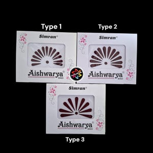 Puede incluir: Tres paquetes de pegatinas bindi decorativas marrones. Cada paquete tiene un diseño diferente de pegatinas bindi. Los paquetes están etiquetados con "Simran" y "Aishwarya Bindi".