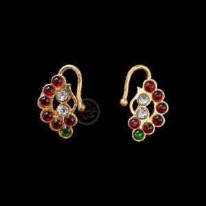 以下が含まれることがあります： 赤、白、緑の石が付いた金の鼻のリングのペア