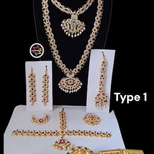 May include: A full gold-coloured jewellery set, including a necklace, earrings, a headpiece, a bracelet, and a waist belt. The set is decorated with red, green, and white gemstones. The text "Type 1" is visible.