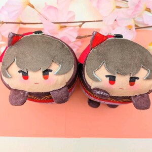 May include: Two plush toys with brown hair and red accents. The toys are wearing red and gold outfits and have a cute, cartoon-like appearance.