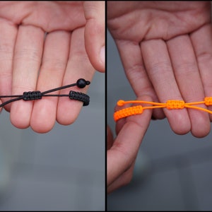 Pode incluir: Duas pulseiras ajust&aacute;veis, uma preta com contas pretas e outra laranja brilhante.