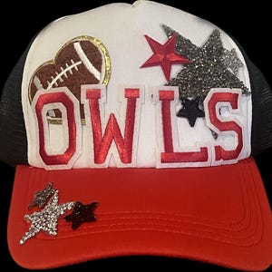 Puede incluir: Gorra de camionero blanca y roja con una malla negra en la parte posterior. La gorra tiene un parche de fieltro rojo con la palabra "OWLS" en letras blancas. La gorra también tiene una estrella roja, una estrella negra y un corazón marrón con un diseño de fútbol.