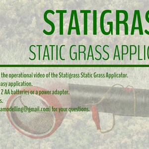 K&ouml;nnte beinhalten: Ein gr&uuml;n-schwarzer statischer Grasapplikator mit einer rot-silbernen D&uuml;se. Der Applikator ist mit "Statigrass Static Grass Applicator" beschriftet und hat einen QR-Code mit dem Text "TT002".