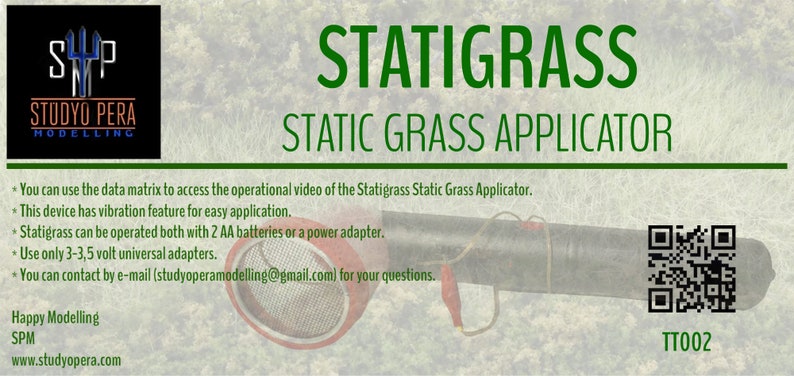 K&ouml;nnte beinhalten: Ein gr&uuml;n-schwarzer statischer Grasapplikator mit einer rot-silbernen D&uuml;se. Der Applikator ist mit "Statigrass Static Grass Applicator" beschriftet und hat einen QR-Code mit dem Text "TT002".