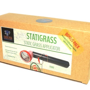 K&ouml;nnte beinhalten: Ein brauner Karton mit einem Etikett, auf dem "Statigrass Static Grass Applicator" steht und ein Bild des Produkts abgebildet ist. Das Produkt ist ein schwarzes Handger&auml;t mit einem roten und silbernen Netz oben. Die Box enth&auml;lt au&szlig;erdem ein Bonus-Paket mit einem 3,5 V/1A Netzteil und einem 150 cm langen Kabel.