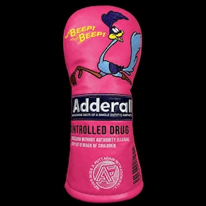 May include: A pink golf club head cover featuring an embroidered Road Runner character with the text BEEP BEEP. The design includes the word Adderall, the phrase CONTROLLED DRUG, and a circular logo with the text NEVER MISS A PUTT AGAIN WITH ADDERALL.