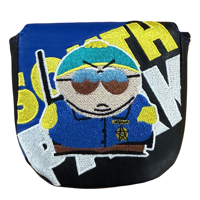 K&ouml;nnte beinhalten: Ein schwarz-blauer Golf-Putter-Schl&auml;gerhaube mit einer gestickten Grafik einer Zeichentrickfigur, die eine t&uuml;rkisfarbene M&uuml;tze, eine braune Sonnenbrille und ein blaues Hemd mit einem gelben Sternabzeichen tr&auml;gt. Der Text SOUTH PARK ist gelb und wei&szlig; gestickt.