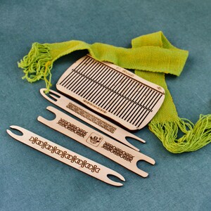 May include: A wooden loom kit with three wooden weaving needles and a green woven scarf. The loom has a Celtic knot design and the text "8.5" Threads" is printed on the loom.