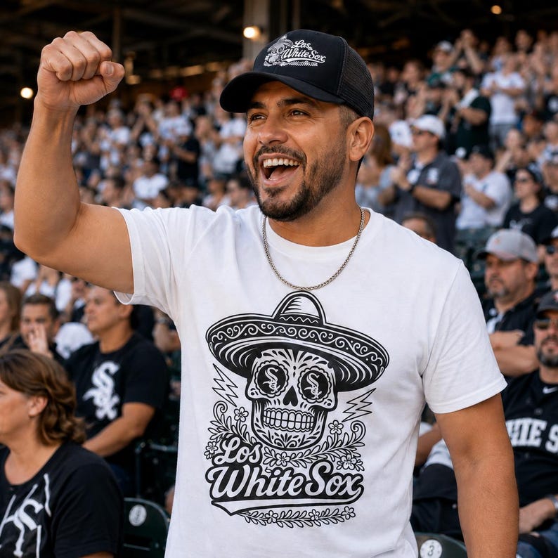 May include: A white short-sleeve t-shirt featuring a black graphic print of a sugar skull wearing a sombrero with the text Los White Sox. The skull design includes floral details and lightning bolts. A black baseball cap is worn with the same text.
