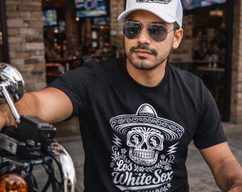 Puede incluir: Una camiseta negra de manga corta con un gráfico blanco de una calavera con sombrero y el texto Los White Sox, junto con una gorra blanca tipo camionero con un gráfico y texto a juego, y gafas de sol de aviador con cristales oscuros.