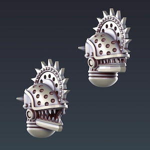 May include: Two metallic, stylized, mechanical head sculptures. Each head features a spiked crown, a dotted helmet, and a jaw with sharp teeth. The design incorporates gears, rivets, and a cylindrical base, all rendered in a silver-gray color.
