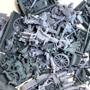 May include: A collection of unpainted grey resin miniature figures and vehicle parts, including wagon wheels, horse-drawn carriages, and various armoured characters in dynamic poses, scattered together in a disorganised pile of hobby gaming components.