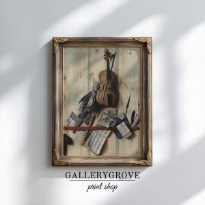 May include: A framed wall art print featuring a violin, a bow, several quill pens, and scattered sheet music arranged on a light-colored wooden surface with vertical stripes. The frame is dark brown with ornate gold-toned corner detailing.