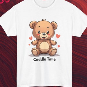 Könnte beinhalten: Weißes T-Shirt mit einem braunen Comic-Bären, der ein rotes Herz auf der Brust trägt. Der Bär sitzt mit ausgestreckten Armen. Der Text "Cuddle Time" ist unter dem Bären gedruckt.