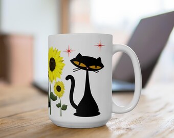 May include: White ceramic mug featuring a black cat illustration with yellow eyes and a long neck, alongside yellow sunflowers. Red starburst accents are also present. The mug has a large handle and is suitable for hot or cold beverages.