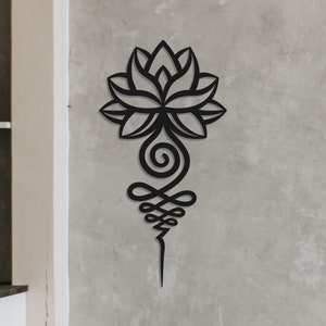 Può includere: Arte da parete in metallo nero con un fiore di loto stilizzato con dettagli intricati. L'arte è montata su una parete grigia in un ambiente da soggiorno.