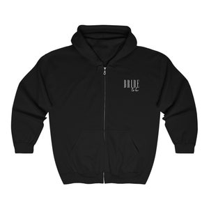 May include: Black zippered hoodie with the text "Bride to be" in white lettering.