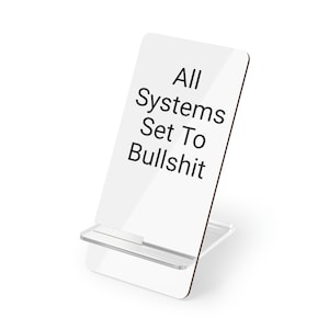 Può includere: Supporto per telefono in acrilico bianco con il testo "All Systems Set To Bullshit" stampato sul davanti.