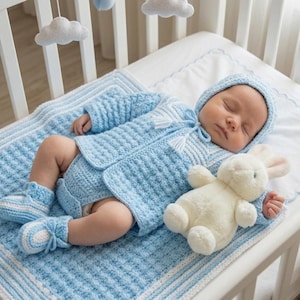 May include: A baby asleep in a white cot, dressed in a light blue knitted outfit, including a hat, jacket, and booties. A white stuffed bunny lies next to the baby on a blue and white knitted blanket. Decorative clouds hang above.