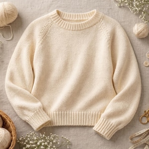 May include: Cream-colored knit sweater with a crew neck and ribbed cuffs and hem. The image includes yarn, knitting needles, scissors, and decorative flowers, suggesting a handmade or craft theme.