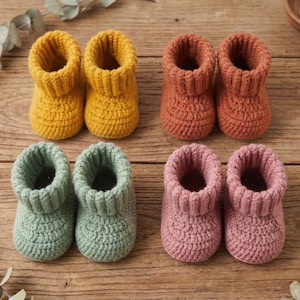 May include: Four pairs of handmade baby booties in various colors: yellow, orange, green, and pink. The booties are crocheted with a ribbed cuff and a textured stitch, perfect for a newborn.