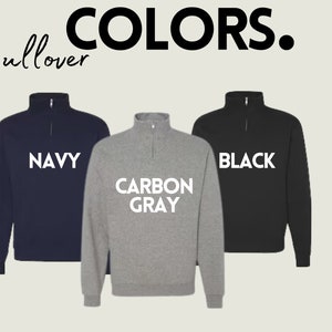 May include: Three pullover sweatshirts in navy, carbon grey, and black. The sweatshirts have a mock neck and a zipper at the neck. The text "NAVY", "CARBON GREY", and "BLACK" is printed in white on the front of each sweatshirt.
