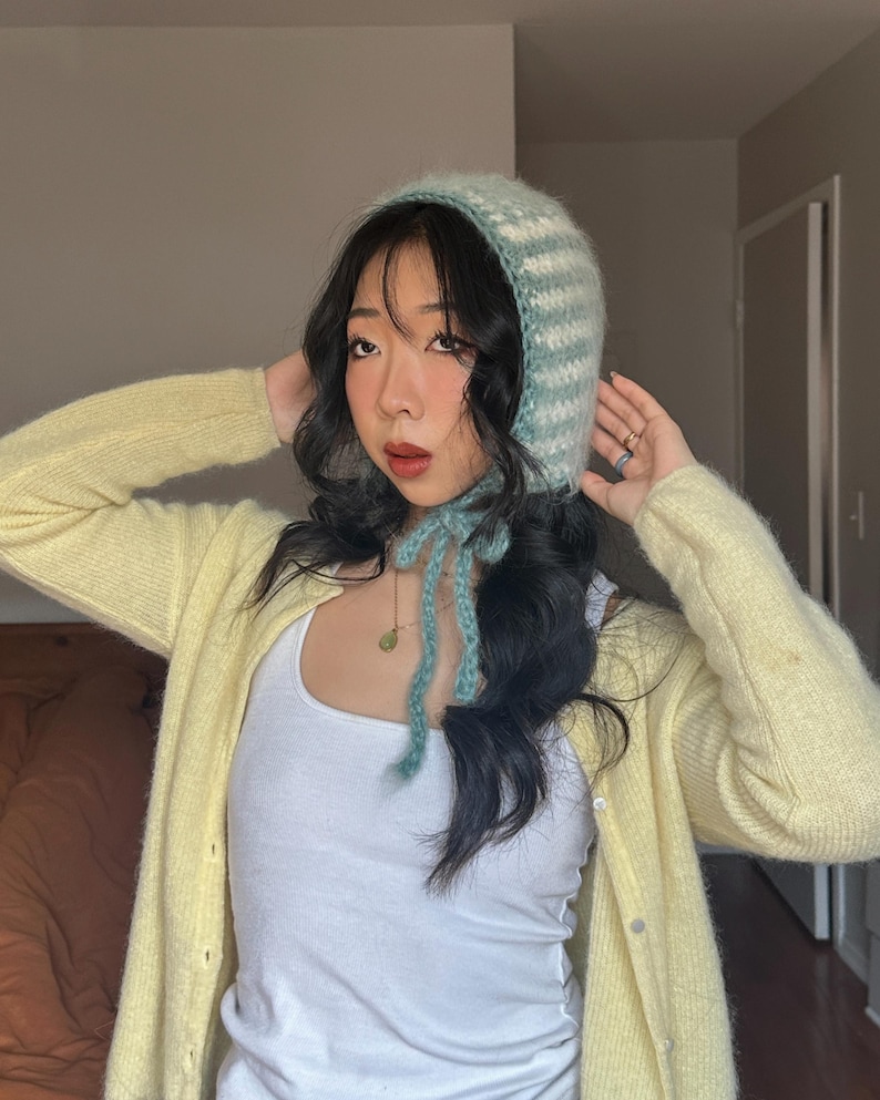 Puede incluir: Un gorro tejido a rayas azules claras y blancas, con cierre de lazo. El conjunto incluye una rebeca amarilla y una camiseta sin mangas blanca. El estilo es suave y c&oacute;modo.