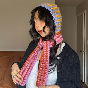 Puede incluir: Conjunto de capucha y bufanda de ganchillo hecho a mano. La capucha es lavanda con rayas amarillas, y la bufanda es rosa y naranja. El conjunto est&aacute; hecho de un hilo suave y texturizado. Un accesorio &uacute;nico y elegante.