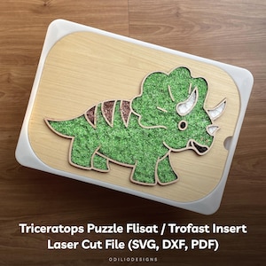 Puede incluir: Un inserto de rompecabezas de Triceratops verde para una unidad de almacenamiento de juguetes Flisat o Trofast. El inserto está hecho de madera y tiene un diseño cortado con láser. La imagen incluye el texto "Triceratops Puzzle Flisat / Trofast Insert Laser Cut File (SVG, DXF, PDF) ODILIODESIGNS".
