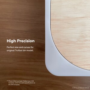 May include: A close-up of a white Trofast insert template for a wooden bin. The template is cut to fit the bin perfectly. The text "High Precision" is visible in the image. The text "Perfect size and curves for original Trofast bin model." is also visible in the image. The text "Photo is from our basic Trofast insert SVG template, which has same specifications as this SVG template." is visible in the image. The text "ODILIODESIGNS" is visible in the image.