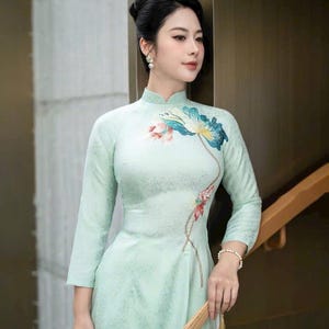 Green brocade Vietnamese traditional Ao Dai long dress with lotus design, including pants