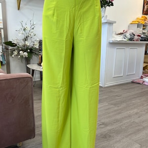 May include: Wide-leg pants in a bright lime green color. The pants have a high waist and a straight leg.