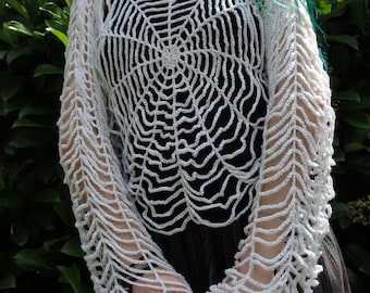 May include: White crochet top with a spiderweb design. The top has long sleeves with a lacy pattern.
