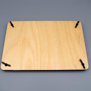 May include: A plain, light brown wooden plaque with four black metal hanging hooks on the corners.