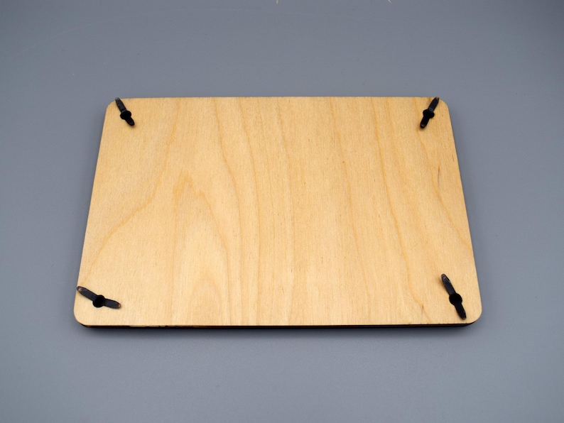 May include: A plain, light brown wooden plaque with four black metal hanging hooks on the corners.
