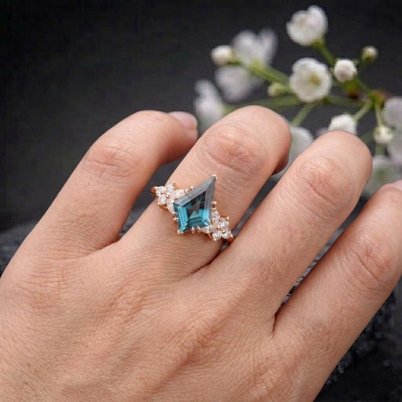 Puede incluir: Un anillo de oro rosa con una gema de color turquesa en forma de cometa. El anillo est&aacute; adornado con peque&ntilde;as gemas claras y detalles florales. Una joya.