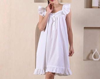 Puede incluir: Un camisón blanco con mangas y dobladillo con volantes. El escote cuadrado está adornado con encaje y el vestido tiene una parte delantera abotonada. El camisón es hasta la rodilla y está hecho de una tela ligera.