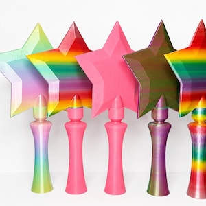 May include: Five colorful star-shaped wands. The stars are in shades of pink, green, red, and rainbow. Each wand has a matching base with a rounded top. The wands are arranged in a row against a white background.