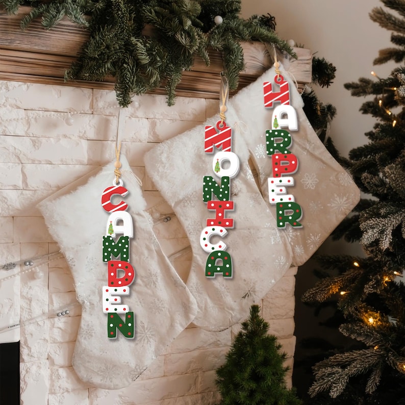 May include: Four personalized Christmas stockings with names "Camden", "Monica", "Harper", and "Ava" written in red, green, and white letters with a festive pattern.