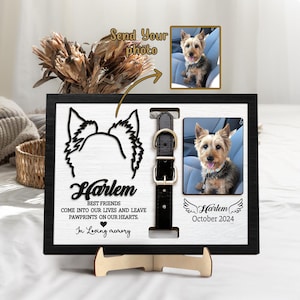 May include: A black framed wooden pet memorial with a photo of a dog, a cutout of a dog's head, and a black leather collar. The text reads "Harlem" and "Best Friends come into our lives and leave pawprints on our hearts."