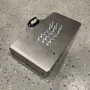 May include: A silver metal plate with a small black light fixture and a set of screws and washers.